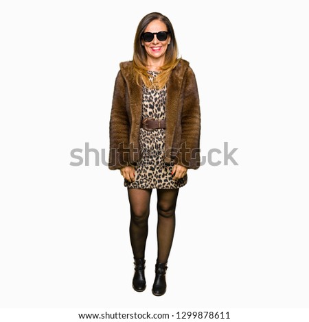 Beautiful middle age elegant woman wearing sunglasses and mink coat with a happy and cool smile on face. Lucky person.