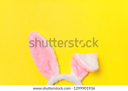 Happy Easter concept. Preparation for holiday. Decorative bunny ears furry fluffy costume toy isolated on trendy yellow background. Simple minimalism flat lay top view copy space