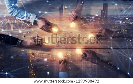 Teamwork and brainstorming concept with businessmen that share an idea with a lamp. Concept of startup. Double exposure Royalty-Free Stock Photo #1299988492