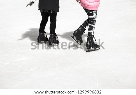 Two teenage girl friends skating on ice on a winter day in New York, USA.