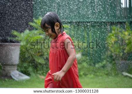 portrait of young kid enjoying playing with water liker rain in the garden