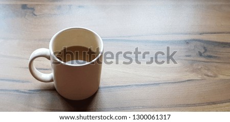A cup of white coffee on the wooden table with natural light from window