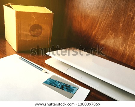 Picture of online business department consist of pen, paper, credit card, laptop and box on wooden work space.