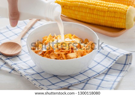 Woman holding bottle of milk pouring milk to cereal corn flakes in bowl, energy health, breakfast daily food.