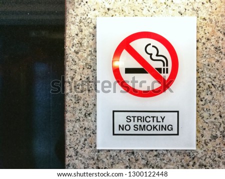 Image of red strictly no smoking sign on reflective white signboard on wall. In relation to recent smoking ban at all restaurants, cafes and eateries by health ministry malaysia government. 