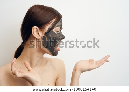 woman in clay mask holds a free space on her hand