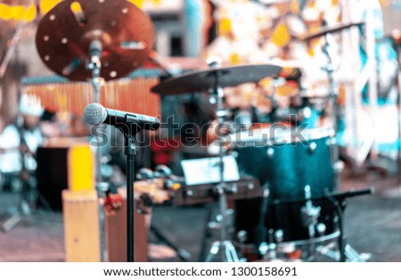 Microphone with drums and other musical instruments on a outdoor stage for performing music. Focus on microphone, blurred background