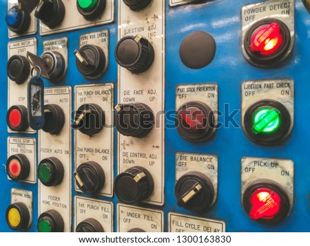 Control panel of industrial machine in the factory, contains many buttons, switches and alarm signal lights.