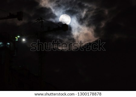 Blurred background of full moon in the cloudy night with tower crane.