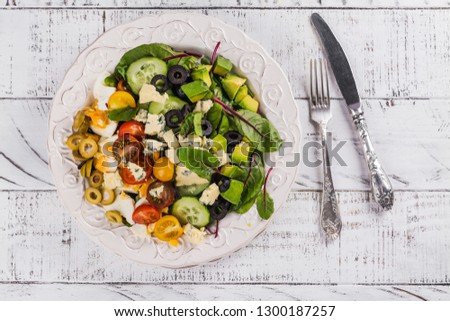 Delicious homemade cobb salad with avocado, egg, beet leaves, olives and tomatoes