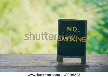 close up small wooden board with no smoking text on old wood table, green nature copy space background, world no tobacco day, medical and healthcare concept