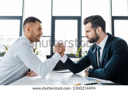 handsome businessmen competing arm wrestling in modern office 