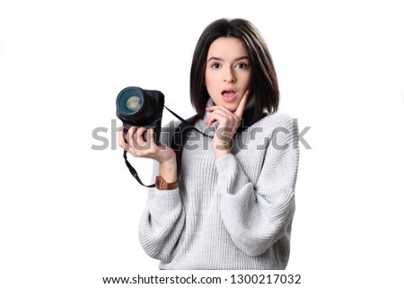 teenage girl in looking at the photo camera in her hands with curious and surprised expression on her face