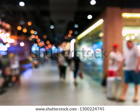Blurred people walking in shopping center with beautiful light bokeh, tourists