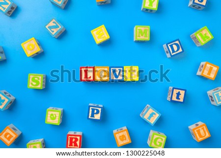 Love. Wooden colorful alphabet blocks on blue background, flat lay, top view. 