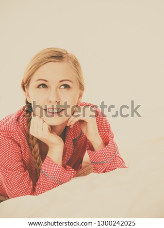 Laziness relax concept. Smiling positive teen girl in bed. Lazy youthful female wearing red dotted pajamas lying on pillow in good mood. Toned image