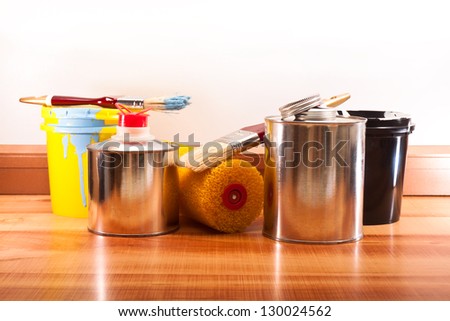 Banks with paints and solvents, brushes and roller on the floor from the parquet Royalty-Free Stock Photo #130024562