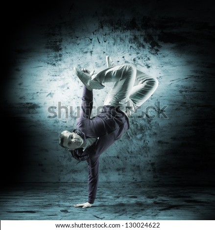 Young and sporty modern dancer over the dramatic background