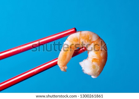 red chopsticks and shrimp on blue background