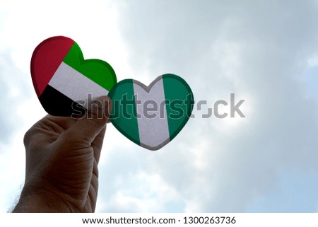 Hand holds a heart Shape UAE and Nigeria flag, love between two countries