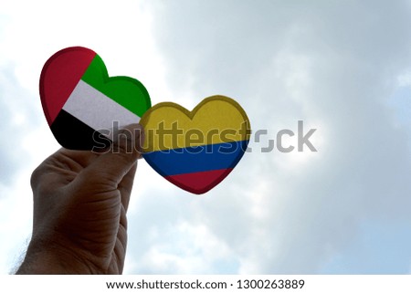 Hand holds a heart Shape UAE and Colombia flag, love between two countries