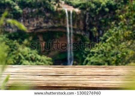 Wooden table on the background of a waterfall on a summer day