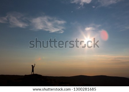 silhouette of a child at sunset against the sky. The edge of the earth. At the edge of the earth. The boy is taking pictures of the sun.