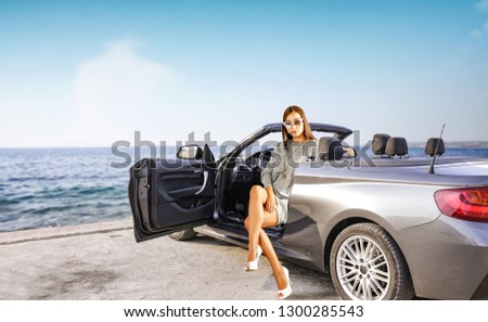 Summer car and slim young woman. Sea landscape with blue sky and free space for your text. 