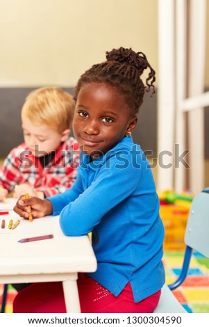 African girl as a pupil or preschooler while painting in preschool or daycare