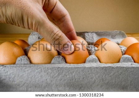 Close up of male hand taking a chicken egg from a cardboard egg box.
