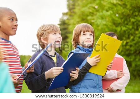 Group of kids together play scavenger hunt at kids birthday with clipboard Royalty-Free Stock Photo #1300319524