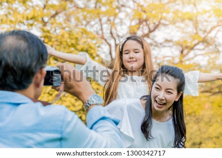 Father taking picture of mother and daughter outdoor.