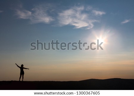 girl silhouette against the sky. The edge of the earth. At the edge of the earth. very beautiful sunset in the mountains. Тhe sun's rays.