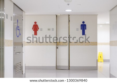 Public toilet that is bright and clean with a male-female sign and the toilet for the disabled is clearly distinguished