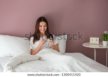 Beautiful young woman playing mobile game in bed at home
