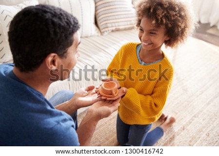 African American pre-teen girl presenting a handmade gift to her father, elevated over shoulder view, close up