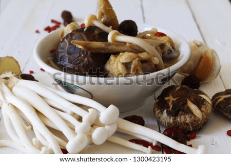 Chinese cuisine. Chicken soup with Tea flower and White beech mushroom, Red dates and Goji berry. Raw ingredient at side on white wooden pallet.