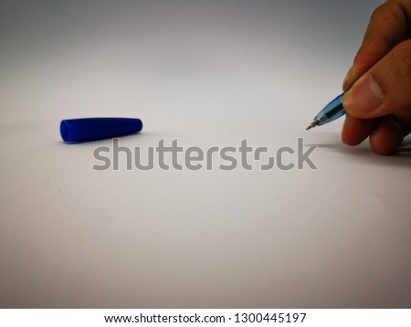 the​ hand​ is​ writing or​ drawing on​ white​ paper