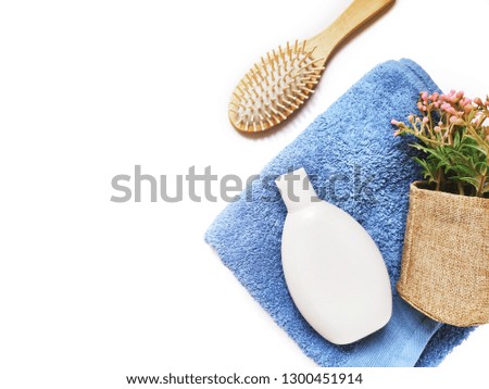 Flat lay beauty still life photography. Organic herbal shampoo, wooden comb, blue cotton terry towel and flowers. Natural cosmetics for hair care