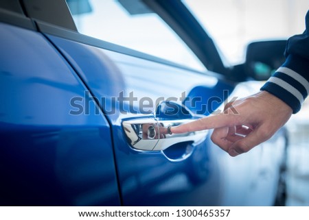 Close-up pictures of men pressing the button by hand and opening a new blue car Car rental concept