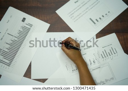 Closeup of business woman hand writing on paper at desk