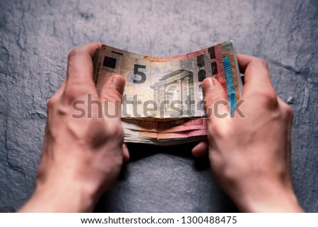 Hand´s of young man holding a money. Banknotes on a stone background. Euro money bank notes of different value. European currency - Euro. Bills of money. Man holding a bills of money.  Royalty-Free Stock Photo #1300488475