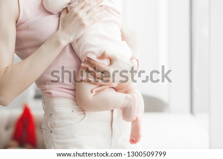 Child`s buttocks picture with copy space. Unrecognizable mother holding her child. Mom and her baby girl indoors.
