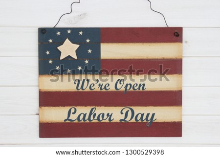 We are open Labor Day text on a retro wood American stars and strip flag sign on weathered wood
