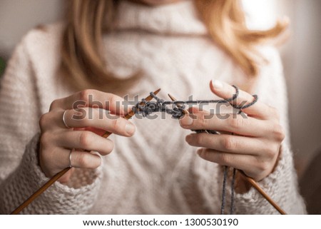 Beautiful woman sitting on the sofa of the living room and knitting for winter at home