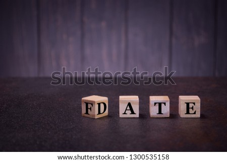 The word date fate on wooden cubes, on a dark background, light wooden cubes signs, symbols signs, business office, site content, still life