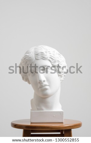 Plaster head, antique sculpture for learning to draw. Standing on a stool on a white background. Studio artist.