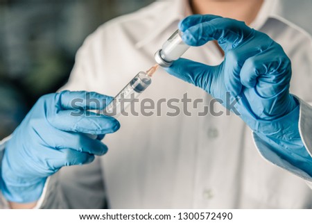 Doctor or nurse holding hpv, rabies, mumps, measles vaccine or medicine with syringe prepare for treatment patient, medicine and drug concept