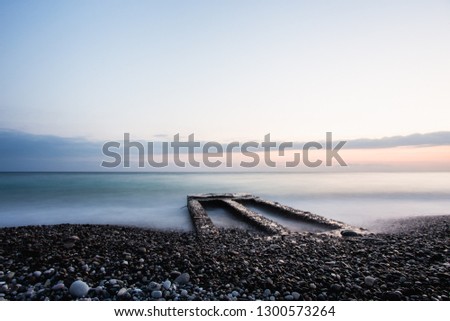 Minimalistic Sunset beach landscape with old pier.Long exposure shot.