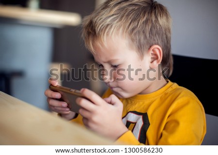 Children, technology and internet concept. Little smiling child boy playing games or surfing internet on digital smartphone